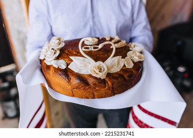 A Man, A Father, Holds A Round Loaf Decorated With Flowers, A Swan With An Embroidered Towel In His Hands. Close-up Wedding Food Photography.