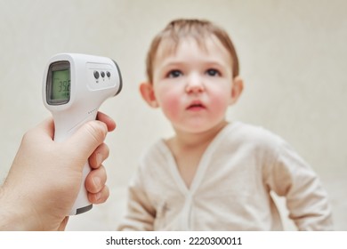 A Man Father Measures The Temperature Of A Sick Toddler Baby With A Thermometer. Dad Checks The High Temperature Of A Sick Child. Kid Aged One Year And Three Months