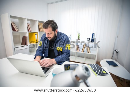 Man FBI agent working in his office on laptop alone