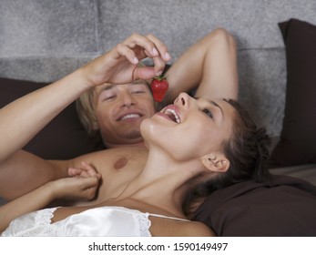 Man Feeding Strawberry To Girlfriend In Bed