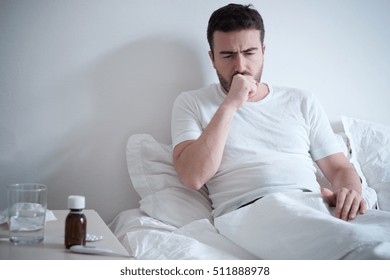  Man feeling bad lying in the bed and coughing - Shutterstock ID 511888978