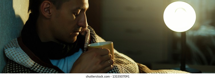 Man feeling cold, lying in the bed and blowing his nose