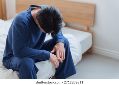 Man feeling depressed while sitting on the bed