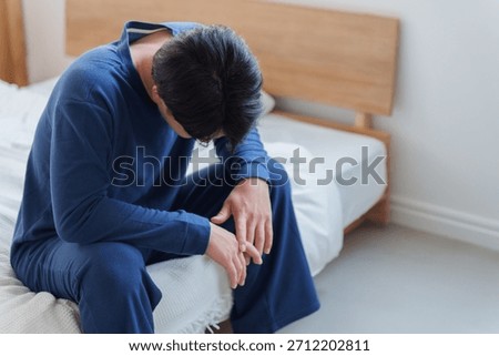 Man feeling depressed while sitting on the bed