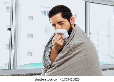 Man Feeling Sick At Home With Flu And Cold Symptoms Blowing His Nose In Handkerchief.