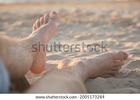 Man feet on the Sand. On a hot summer day, a guy is lying on the sand.