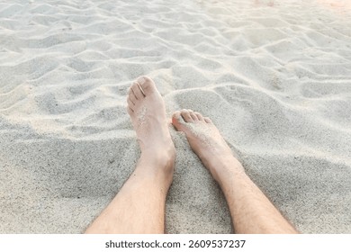 Man feet sitting on hot sand over the sea. Holiday concept. Man feet relaxing on beach, enjoying sun and splendid view. barefoot sunbathing on summer beach. Happy on holidays vacation concept