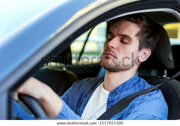 Man\
fell asleep behind steering wheel of car. Sleepy driver is riding\
in automobile. Male is violating rules of road. Driving without\
rest concept. Deadly danger on route of modern\
city.