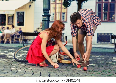 Man Fell Down From The Bicycle And Woman Help Him To Collect Products