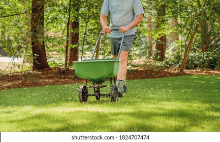 Man fertilizing and seeding residential backyard lawn with manual grass fertilizer spreader. - Shutterstock ID 1824707474