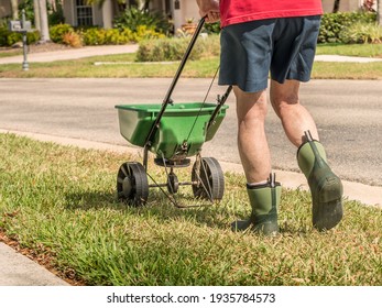 Man fertilizing and seeding residential lawn with manual grass seed spreader. - Shutterstock ID 1935784573