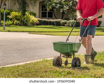 Man Fertilizing And Seeding Residential Lawn With Manual Grass Seed Spreader.