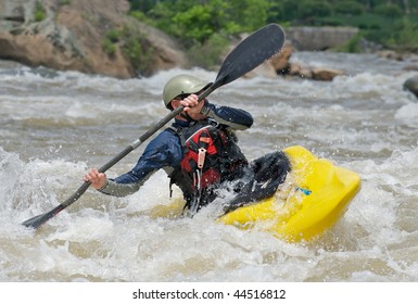 Man Fighting The Rapids Of A River In A Kayak.