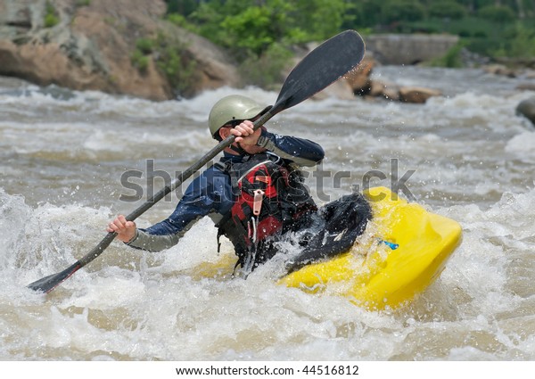 Man fighting\
the rapids of a river in a\
kayak.