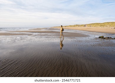 Man figure on the North sea beach with the sandy dunes in the background not far from Den Helder town in the province of North Holland, the Netherlands - Powered by Shutterstock