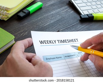 Man Filing In Weekly Timesheet For Employee In The Office.