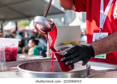 A Man Is Filling Fermented Red Carrot Juice Into A Plastic Glass In A Traditional Food Festival In Turkey Country, Close Up