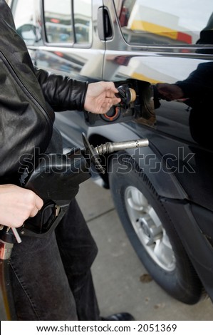 Man filling fuel tank of SUV on american gas station