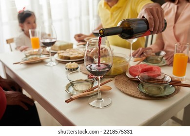 Man Filling Glass Of Tet Dinner Guest With Red Wine