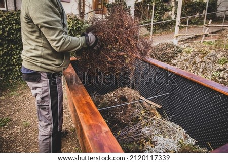 Man filling green waste and plant cuttings into raised bed, gardening