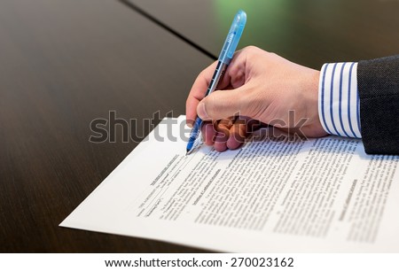 Man filling in Non-Disclosure Agreement NDA - A businessman working on a sheet of paper document
