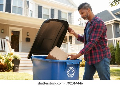 Man Filling Recycling Bin On Suburban Street