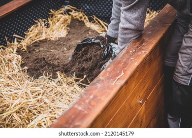 Man filling straw and soil into the raised bed, bodypart gardener