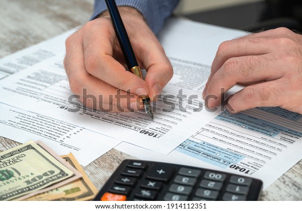 Man filling US tax form.\
Tax form us business income office hand fill concept. Tax Return\
Form 1040