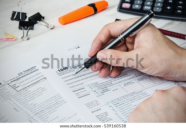 Man filling US tax form. tax form us business\
income office hand fill\
concept