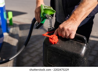 A Man Fills Fuel In A Plastic Can At A Gas Station