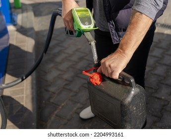 A Man Fills Fuel In A Plastic Can At A Gas Station