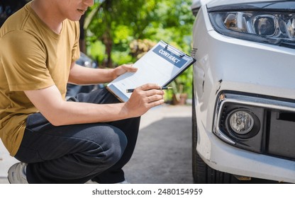 Man fills out a car insurance form after a car accident. Comprehensive motor insurance covers car damage. He files a claim report, speaking with an adjuster to understand his coverage and deductible. - Powered by Shutterstock