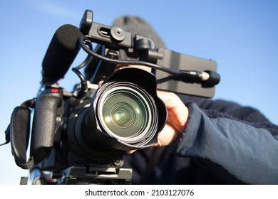 man filming with 4k camcorder against the background of blue sky