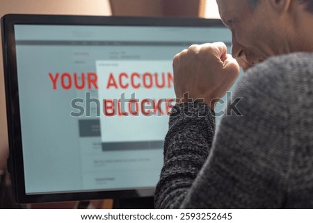 Man with financial problems trying to make online payment. Man frustrated, staring at monitor with account freeze, payment block, and card lock alert
