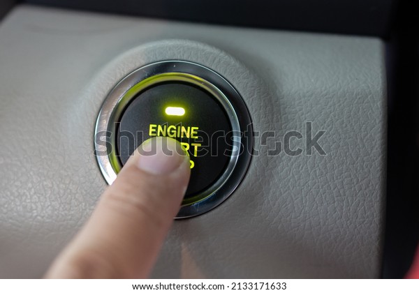 Man finger on pushing a start ignition button\
switch in the modern luxury\
car