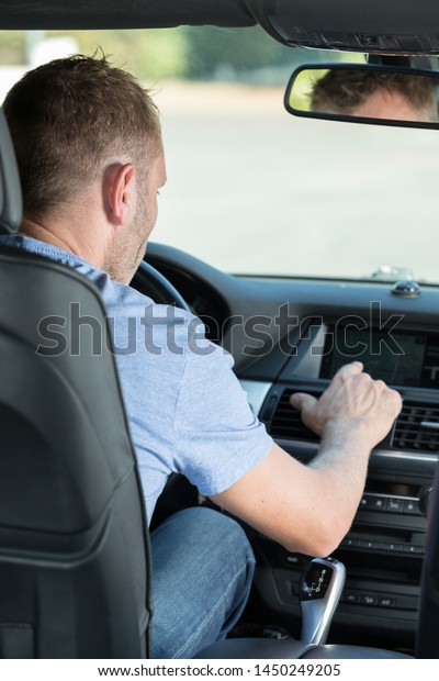 man finger pressing the emergency lights button\
while driving