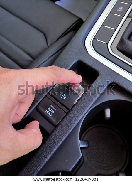 A man fingger push/pull the\
Electric electronic Parking Brake with Auto-hold on modern\
vehicle