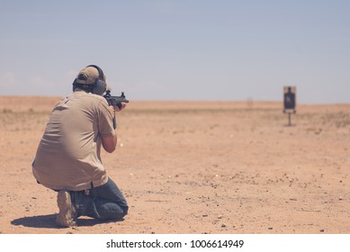 Man Firing Black Rifle On Desert Range With Target In Background