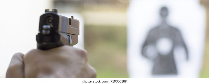 Man Firing Pistol At Target In Shooting Range