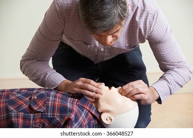 Man In First Aid Class Performing Mouth To Mouth Resuscitation On Dummy