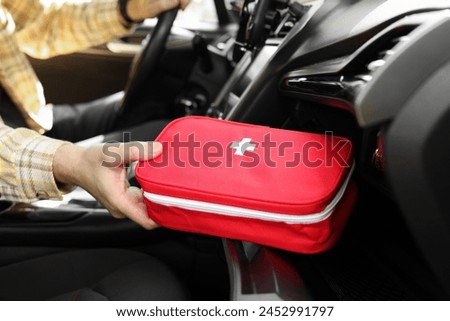 Man with first aid kit inside car, closeup