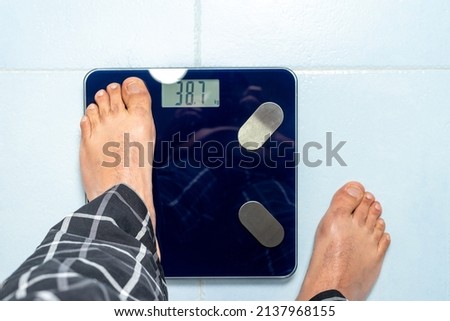 Man first places one foot on the weight scale to start the measurement. Weight control concept. High quality photo