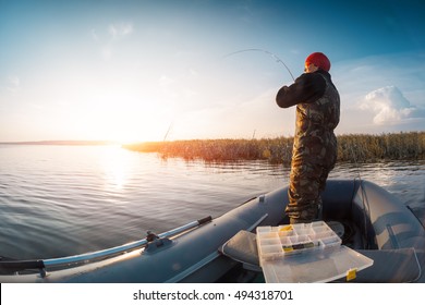 Man Fishing From The Boat On The Lake At Sunset