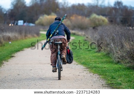 man with fishing gear on bicycle, rear view
