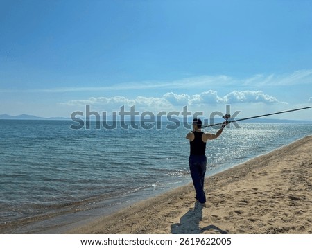 Man fishing on beach at sunset, catching fish rod into calm sea or ocean, outdoor adventure, relaxing vacation, fisherman silhouette, fishing hobby concept. Fisherman for pike, perch, carp.