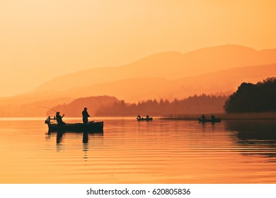 Man Fishing On Lake From Boat At Sunset. Lake Of Menteith, Stirlingshire, Scotland, UK