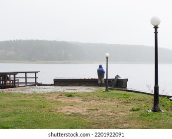 Man Fishing On The Pier, On A Rainy And Foggy Day