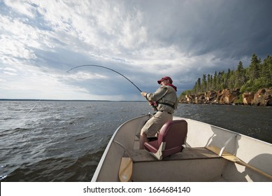 A Man Fishing From An Open Boat Offshore. A Fish On The Line. The Fishing Rod Bending From The Weight.