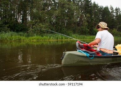 Man Fishing In River From Canoe