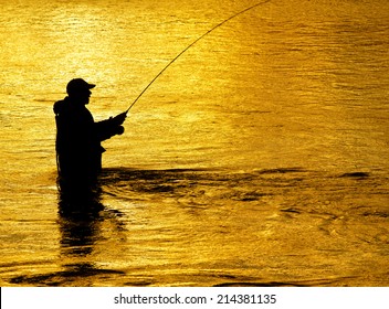 Man fishing in river with fly rod and waders